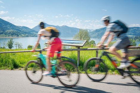 Zwei Personen auf Fahrrädern durch Geschwindigkeit unscharf, fahren auf einem Weg an einem See entlang